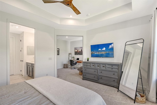 bedroom featuring a tray ceiling, light carpet, ceiling fan, and baseboards