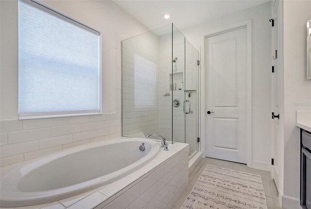 bathroom featuring a stall shower, a bath, and vanity