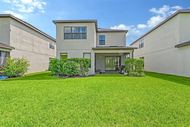 back of property with a sunroom, a lawn, and stucco siding