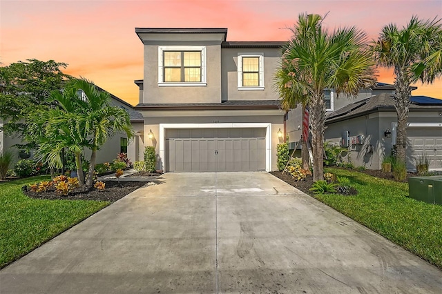 view of front of property with a front yard, concrete driveway, an attached garage, and stucco siding