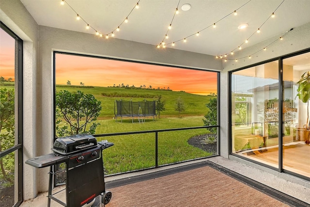 sunroom / solarium featuring a rural view and track lighting