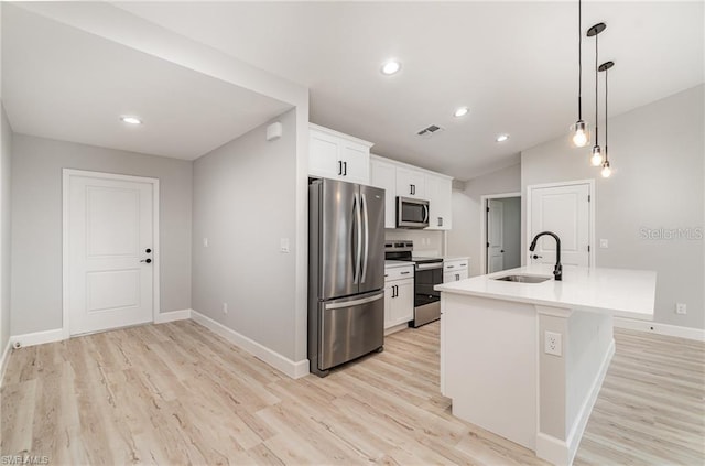 kitchen with stainless steel appliances, sink, hanging light fixtures, white cabinets, and light hardwood / wood-style floors