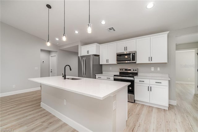 kitchen featuring decorative light fixtures, a center island with sink, stainless steel appliances, sink, and white cabinetry