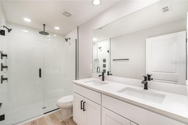 bathroom with vanity, toilet, wood-type flooring, and a shower with shower door