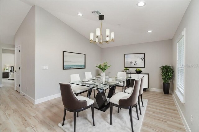 dining area featuring lofted ceiling, a wealth of natural light, a notable chandelier, and light hardwood / wood-style floors