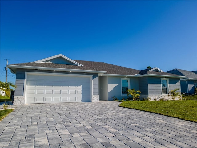 ranch-style home with an attached garage, decorative driveway, and a front lawn