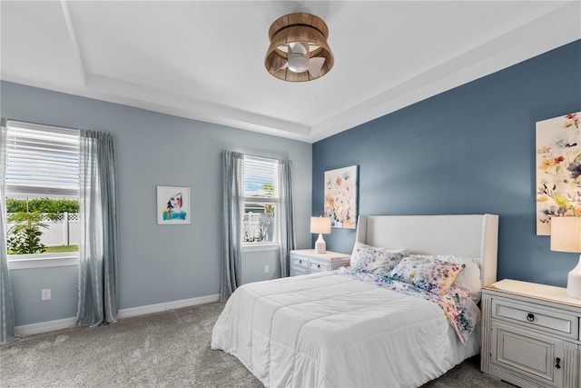 bedroom with a tray ceiling and light colored carpet