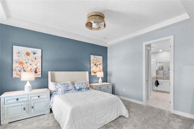 carpeted bedroom with a tray ceiling and ensuite bathroom