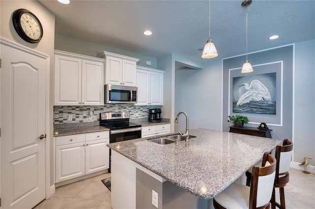 kitchen featuring sink, appliances with stainless steel finishes, white cabinetry, and a kitchen island with sink