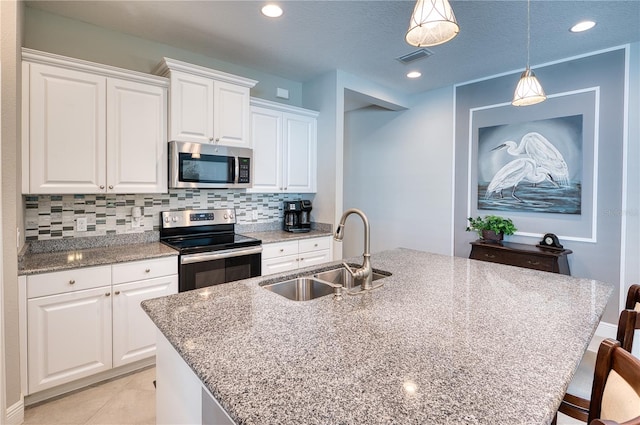 kitchen featuring white cabinetry, stainless steel appliances, sink, hanging light fixtures, and a center island with sink