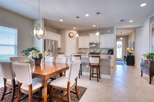 tiled dining area featuring a textured ceiling and an inviting chandelier