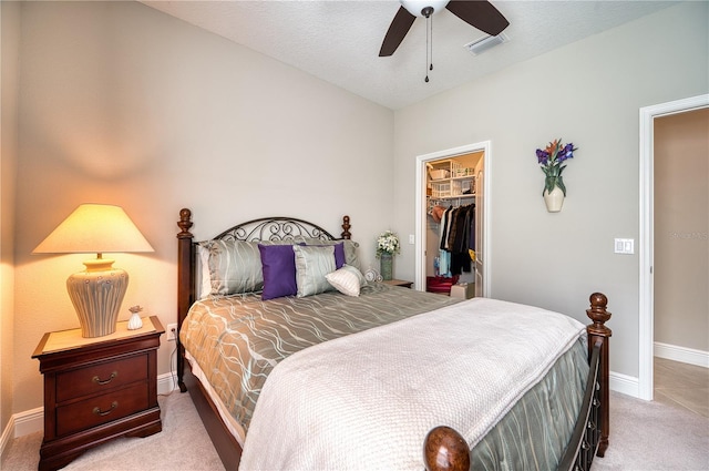 carpeted bedroom featuring a textured ceiling, ceiling fan, a walk in closet, and a closet