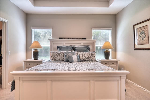 carpeted bedroom featuring multiple windows and a raised ceiling