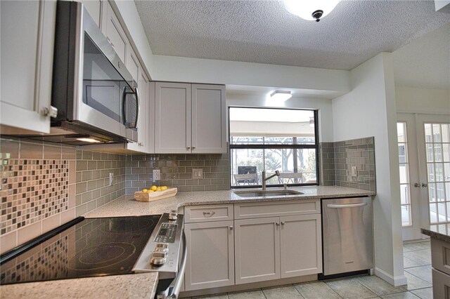 kitchen with light tile patterned floors, appliances with stainless steel finishes, tasteful backsplash, and sink