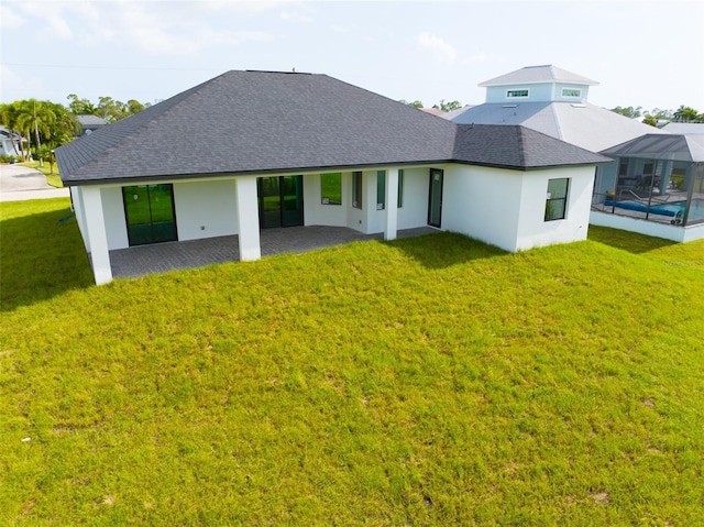 back of property featuring glass enclosure, a patio area, and a yard