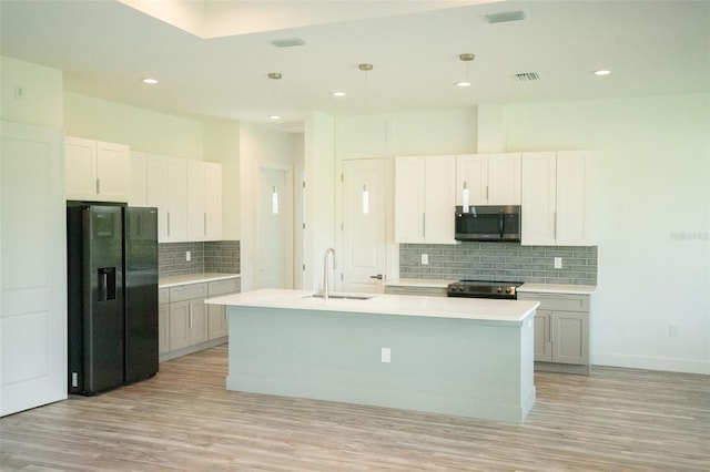 kitchen featuring a kitchen island with sink, pendant lighting, light hardwood / wood-style flooring, and stainless steel appliances