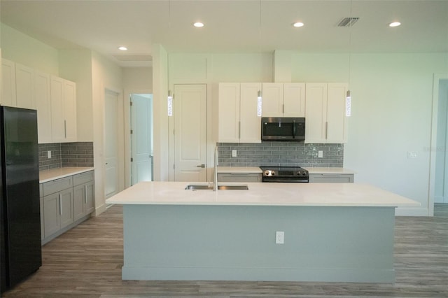 kitchen with hardwood / wood-style floors, stainless steel appliances, a kitchen island with sink, and sink