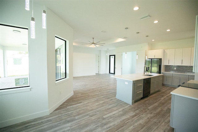 kitchen featuring stainless steel fridge, sink, an island with sink, ceiling fan, and hardwood / wood-style flooring