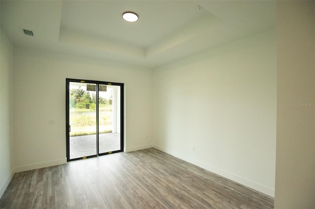 unfurnished room with light wood-type flooring and a tray ceiling