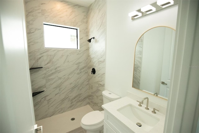 bathroom featuring vanity, toilet, and a tile shower