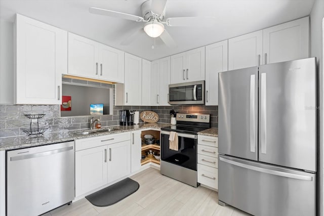 kitchen with stone counters, sink, backsplash, stainless steel appliances, and white cabinets