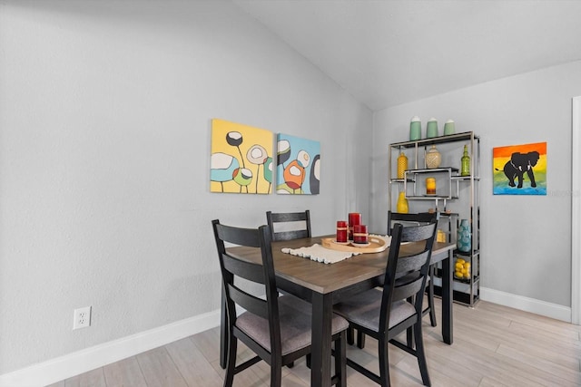 dining space with vaulted ceiling and light hardwood / wood-style flooring