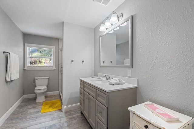 bathroom featuring vanity, toilet, a shower with shower door, and hardwood / wood-style floors