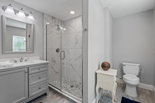 bathroom featuring vanity, toilet, wood-type flooring, and a shower with shower door