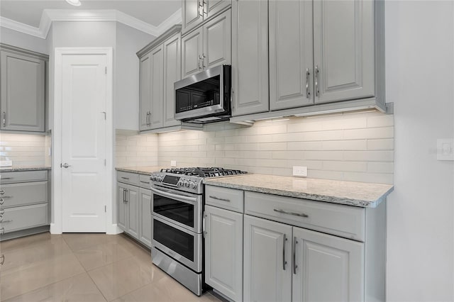 kitchen with gray cabinets, crown molding, tasteful backsplash, light tile patterned floors, and stainless steel appliances