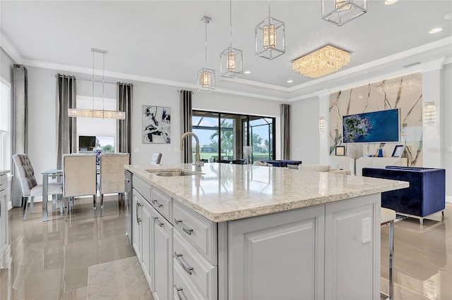 kitchen with white cabinetry, an island with sink, sink, and hanging light fixtures