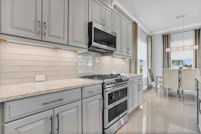 kitchen featuring gray cabinetry, light stone countertops, appliances with stainless steel finishes, hanging light fixtures, and ornamental molding