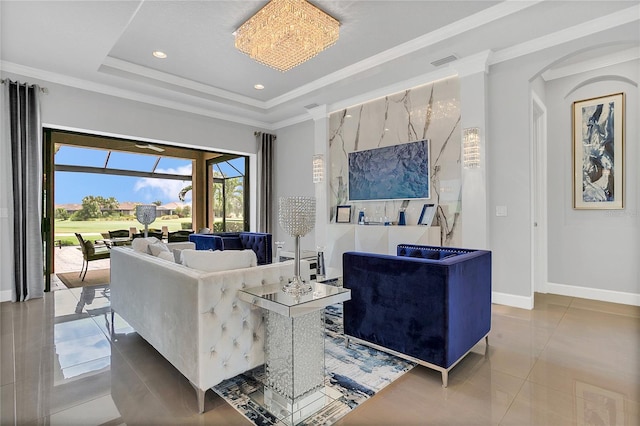 living room with crown molding, a raised ceiling, a chandelier, and tile patterned flooring