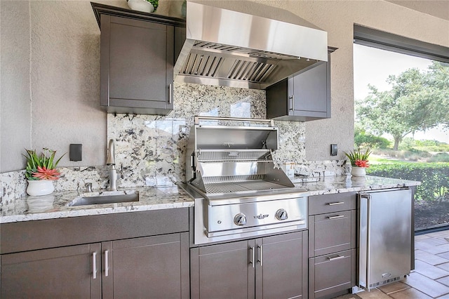 kitchen featuring a wealth of natural light, backsplash, stainless steel fridge, and wall chimney range hood