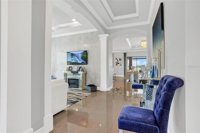 hall featuring a tray ceiling, decorative columns, tile patterned flooring, crown molding, and tile walls