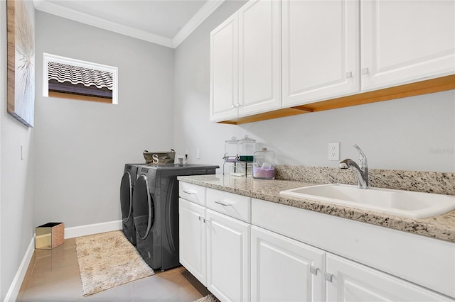 laundry area featuring ornamental molding, cabinets, washing machine and dryer, and sink