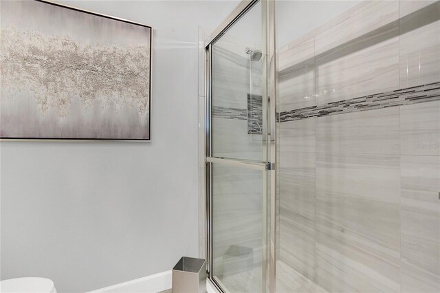 bathroom featuring toilet and a shower with shower door