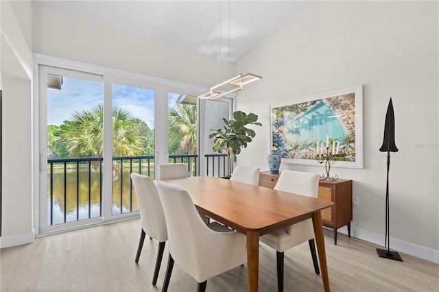 dining space featuring light hardwood / wood-style flooring, lofted ceiling, and a water view