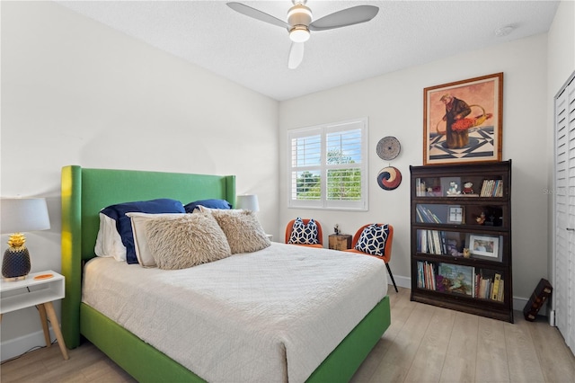 bedroom with light hardwood / wood-style floors, a textured ceiling, and ceiling fan