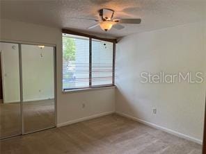 unfurnished bedroom featuring a closet, ceiling fan, light colored carpet, and a textured ceiling