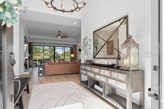 foyer entrance featuring ceiling fan with notable chandelier, light wood-type flooring, and ornamental molding