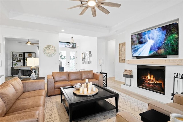 living room with an inviting chandelier, a tray ceiling, crown molding, and light hardwood / wood-style floors