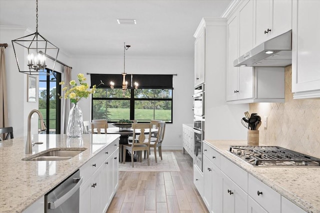 kitchen featuring light stone countertops, appliances with stainless steel finishes, a notable chandelier, and ornamental molding