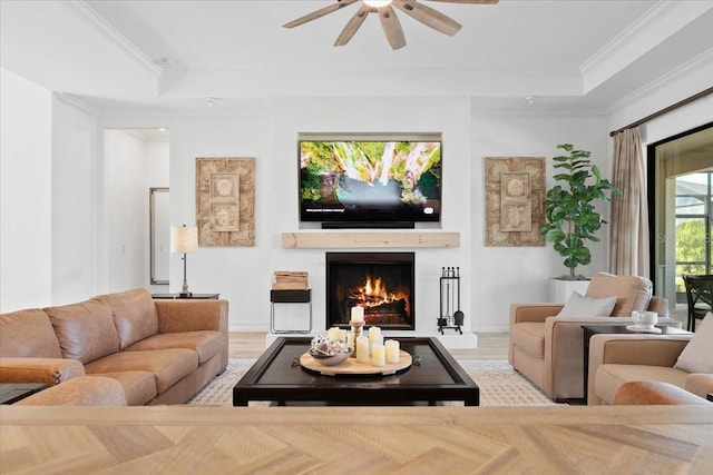 living room featuring a raised ceiling, ceiling fan, and crown molding