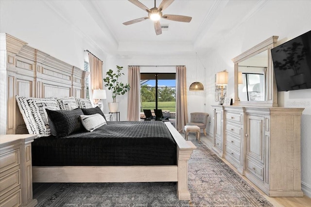 bedroom featuring hardwood / wood-style floors, ceiling fan, a raised ceiling, and access to exterior