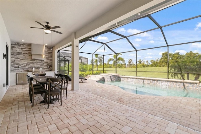 view of pool with an outdoor kitchen, pool water feature, ceiling fan, and a patio area