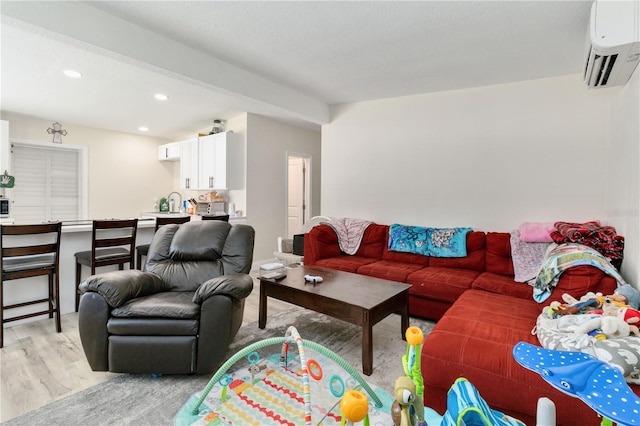 living room featuring a textured ceiling, an AC wall unit, and light hardwood / wood-style floors