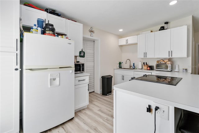 kitchen with white fridge, sink, white cabinetry, and light hardwood / wood-style flooring