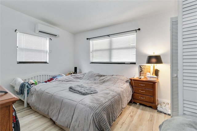 bedroom with light wood-type flooring and a wall unit AC