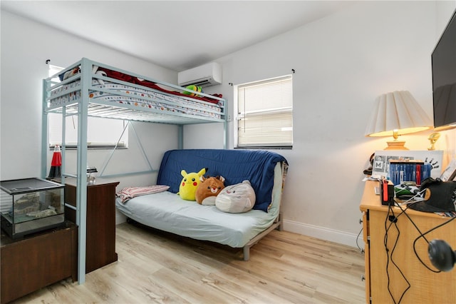 bedroom with a wall unit AC and light hardwood / wood-style flooring