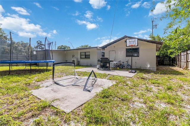 rear view of property featuring a patio area, a yard, and a trampoline